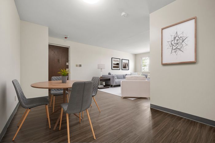Modern open-concept living room with hardwood floors and stylish furnishings, featuring a cozy dining area and elegant wall art.