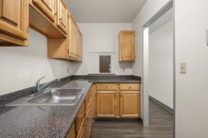 Charming kitchen with warm wood cabinets, sleek granite countertops, and stainless steel sink, perfect for culinary enthusiasts.