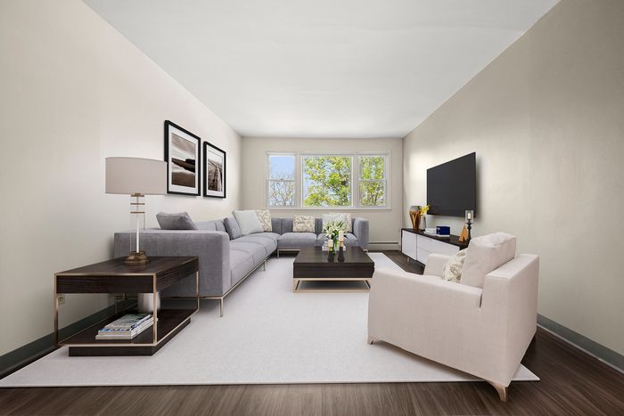 Inviting living room with a modern gray sectional sofa, stylish decor, and large windows offering natural light and serene views.