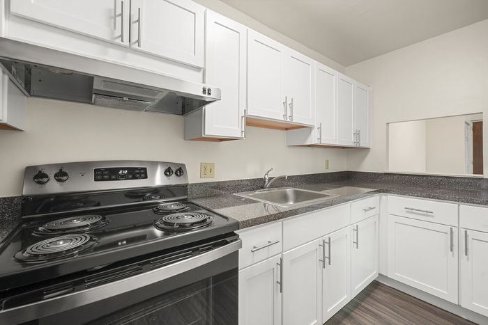 Modern kitchen featuring sleek white cabinetry, stainless steel appliances, and elegant granite countertops.