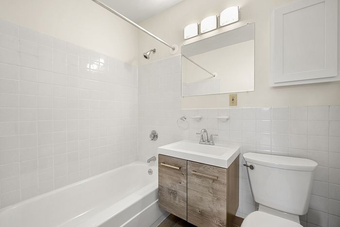 Bright, modern bathroom featuring a sleek vanity, full bathtub, and elegant lighting fixtures.