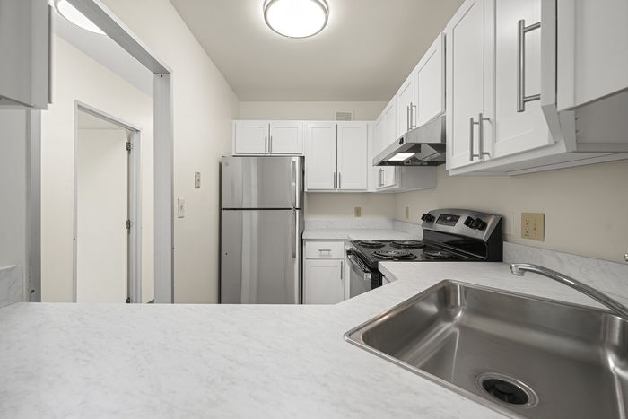 Bright modern kitchen with stainless steel appliances, sleek white cabinetry, and elegant countertops.