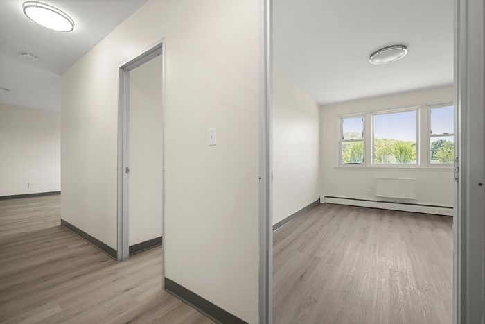 Bright and inviting room with large windows overlooking lush greenery, featuring sleek hardwood floors and elegant, modern lighting.