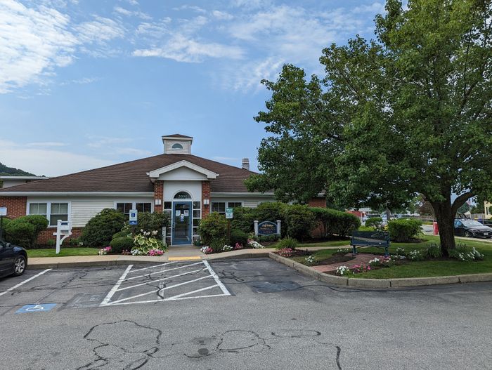 Charming residential building with a welcoming entrance, surrounded by lush greenery and vibrant flowers, perfect for a serene living experience.