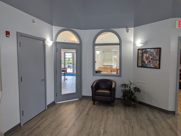 Inviting lobby area with stylish gray doors, modern wood flooring, and a cozy leather chair, perfect for welcoming guests.