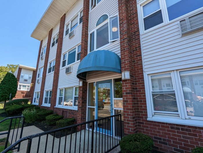 Charming brick apartment building exterior with modern windows, an inviting entrance, and manicured landscaping.