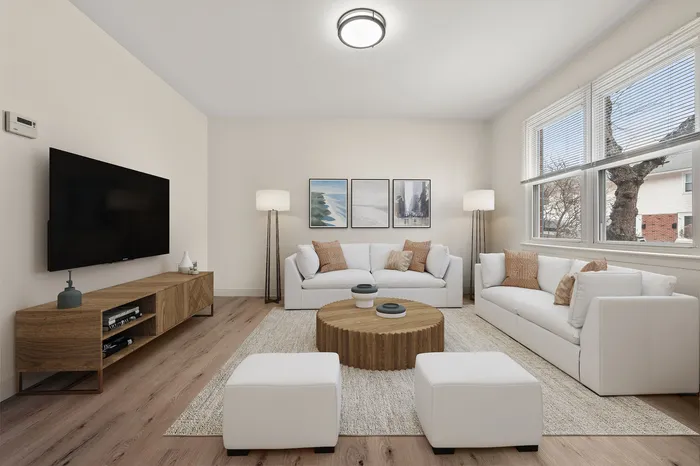Bright and inviting living room with modern decor, featuring large windows, cozy white sofas, and a stylish wooden coffee table, perfect for relaxation and entertainment.