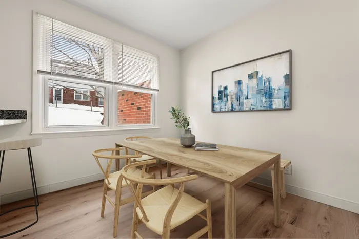 Bright and modern dining room with large windows, stylish wooden table and chairs, cityscape artwork, and sleek light wood flooring.