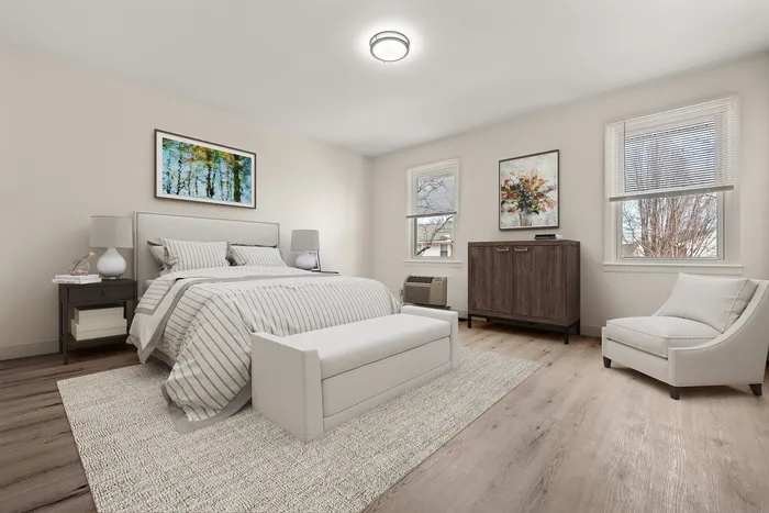 Bright and elegant bedroom featuring a cozy bed with striped linens, modern furnishings, and large windows with natural light.