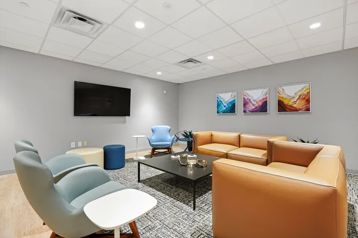 Modern living room with cozy seating, vibrant abstract art, and sleek furniture, offering a chic and welcoming atmosphere.