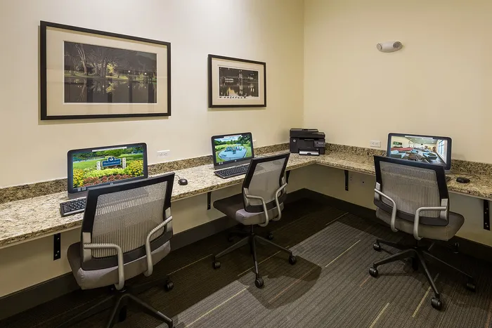 Modern business center with three computer workstations, granite countertops, and elegant decor, ideal for professionals seeking a productive environment.