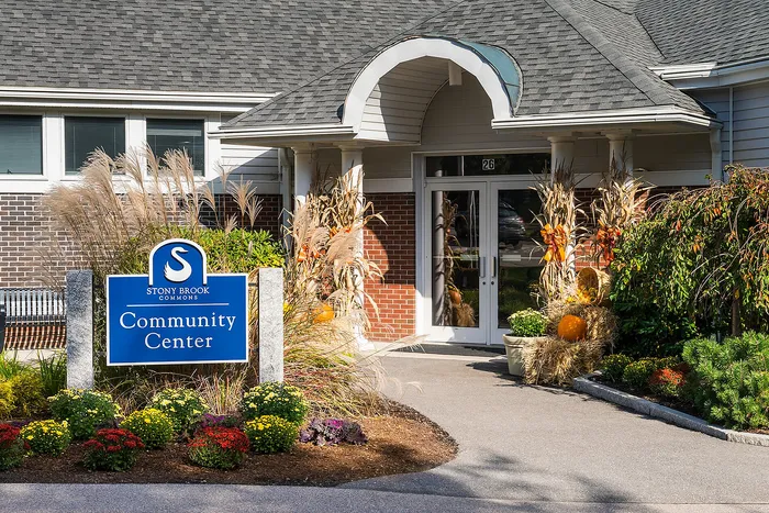 Inviting entrance of the Stony Brook Commons Community Center with vibrant fall decor and lush landscaping.