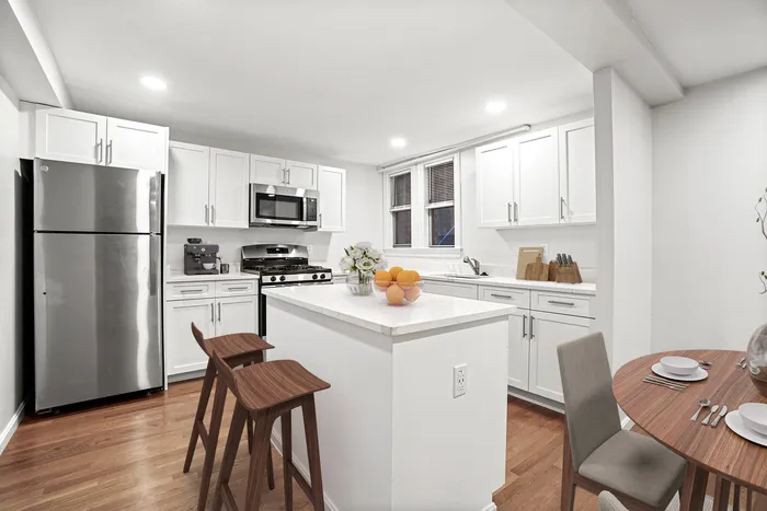 Modern kitchen with sleek stainless steel appliances, elegant white cabinetry, and a cozy breakfast nook with stylish seating.