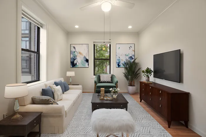 Charming living room with elegant decor, featuring a cozy beige sofa, lush greenery, modern artwork, and a sleek wall-mounted TV.