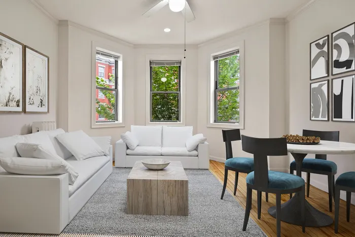 Bright and spacious living room with large windows, modern decor, cozy seating, and stylish dining area.