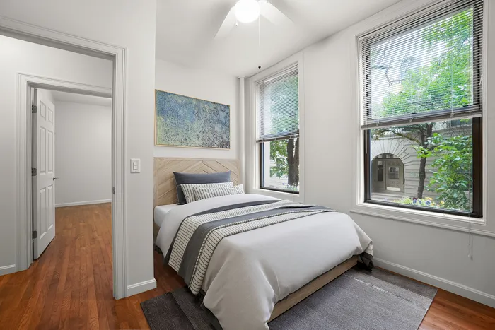 Bright and inviting bedroom with elegant hardwood floors, large windows with a picturesque view, and modern decor.