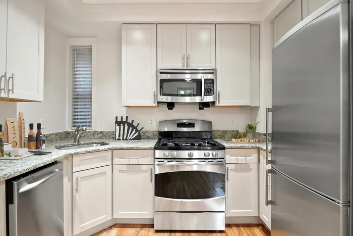 Modern kitchen with sleek stainless steel appliances, granite countertops, and elegant cabinetry.