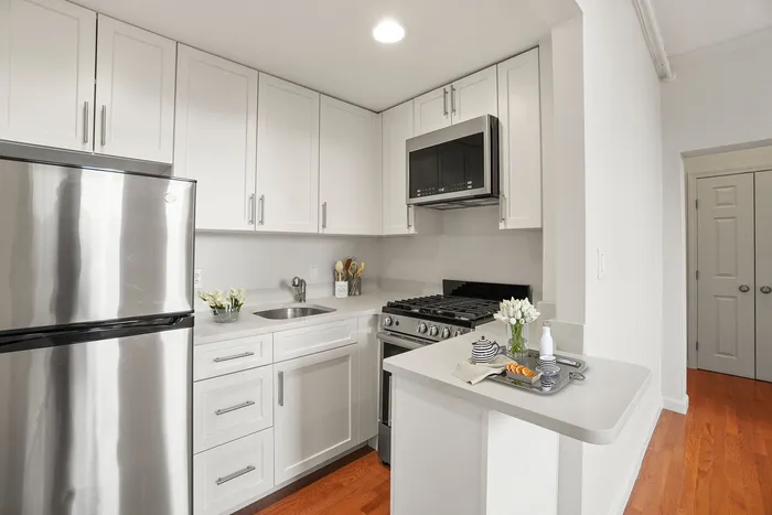 Modern kitchen with sleek stainless steel appliances, elegant white cabinetry, and warm hardwood floors, perfect for culinary enthusiasts.