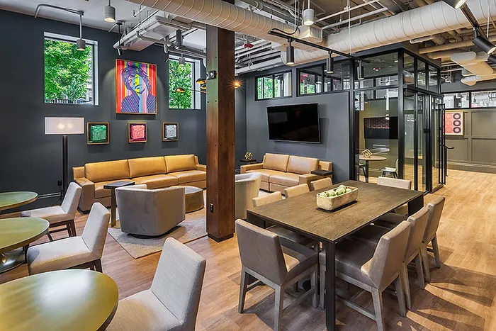 Contemporary communal lounge with stylish seating, vibrant artwork, and natural light in a modern apartment setting.