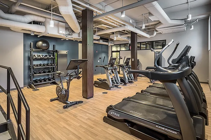 Modern fitness center with state-of-the-art treadmills, exercise bikes, and weightlifting equipment on sleek hardwood flooring.