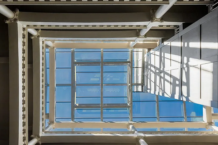 Innovative architectural skylight with a modern glass and metal design, offering a stunning view of the blue sky above.