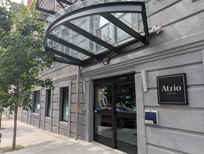 Modern apartment building entrance with stylish glass canopy and sleek signage at Atrio Boston.
