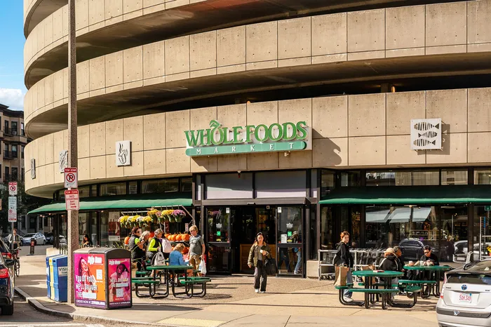 Vibrant urban scene outside a popular retail store with people enjoying outdoor seating and lush greenery.