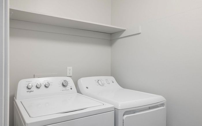 Bright and modern laundry room featuring energy-efficient washer and dryer with convenient overhead shelving.