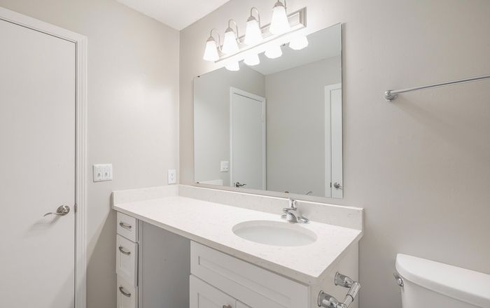 Bright and modern bathroom featuring a sleek white vanity, elegant mirror, and polished fixtures.