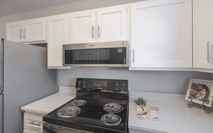 Modern kitchen with sleek white cabinets, stainless steel appliances, and stylish countertop decor.
