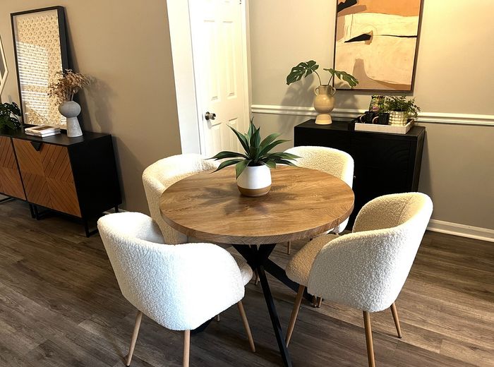 Chic dining area showcasing a round wooden table with plush white chairs, complemented by modern decor and indoor plants.