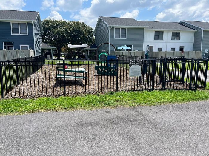Charming pet-friendly community featuring a fenced bark park with benches and playful structures, surrounded by modern residential buildings.