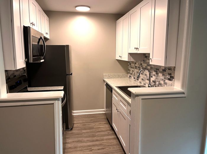 Chic modern kitchen with sleek stainless steel appliances, elegant white cabinetry, and sophisticated tile backsplash.