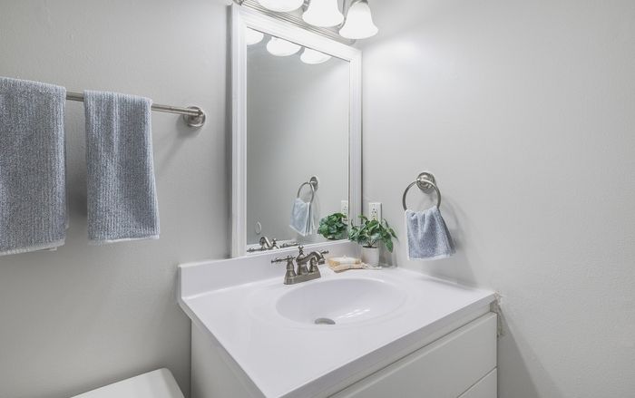 Elegant bathroom featuring a pristine white vanity with a sleek mirror, complemented by soft blue towels and a touch of greenery for a refreshing vibe.