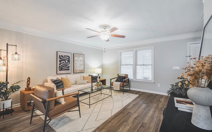 Bright and inviting living room showcasing modern decor, elegant framed artwork, and comfortable seating on warm wooden flooring.