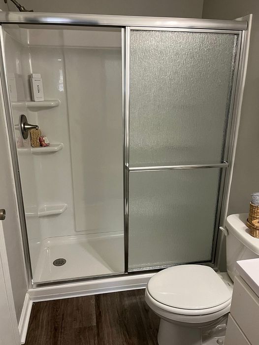 Elegant bathroom with modern glass shower doors and sleek wood flooring.