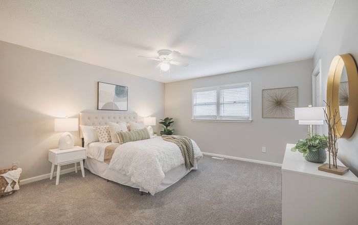 Inviting bedroom with plush carpeting, elegant decor, and large windows providing natural light.