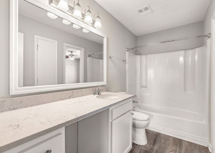 Elegant bathroom with a modern design features a large mirror, stylish lighting fixtures, a sleek marble countertop, and a spacious bathtub.