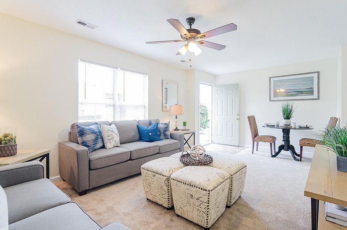 Bright and inviting living room with modern gray sofas, chic decor, and a cozy dining area with natural light.