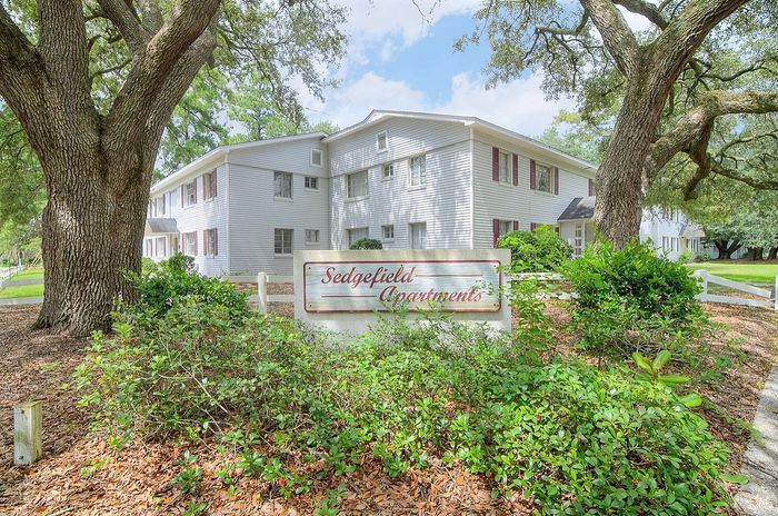 Charming Sedgefield Apartments surrounded by lush greenery and mature trees, offering a serene and inviting community setting.