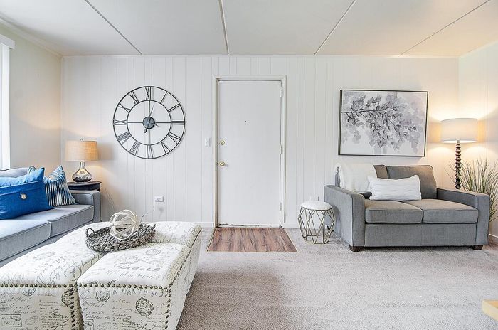 Elegant living room with cozy gray sofa, stylish clock, and modern decor, showcasing a bright and inviting atmosphere.