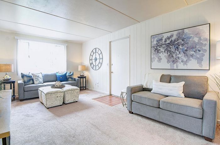 Bright and inviting living room featuring modern gray sofas, stylish decor, and ample natural light, perfect for relaxation.