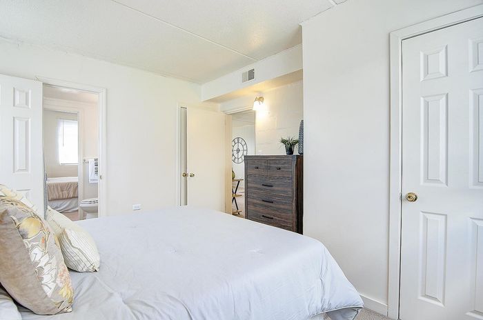 Bright and airy bedroom with modern decor, featuring a plush bed, sleek dresser, and cozy atmosphere.