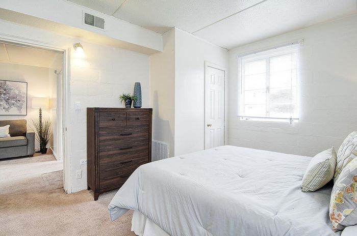 Bright and inviting bedroom with modern decor, featuring a cozy bed, stylish dresser, and abundant natural light from a large window.