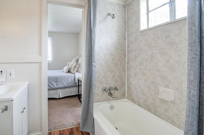 Bright bathroom with elegant tilework leading to a cozy bedroom featuring soft natural lighting and plush bedding.