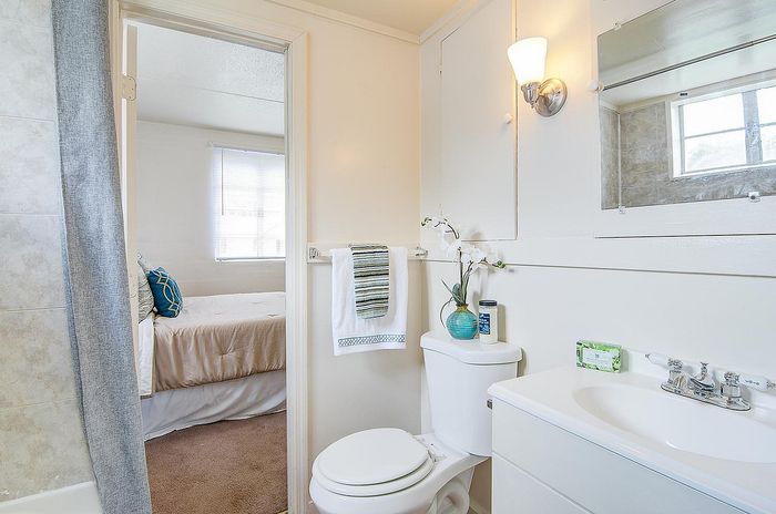 Bright, inviting bathroom with elegant fixtures and adjacent view into a cozy bedroom featuring soft lighting and comfortable bedding.