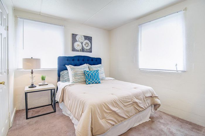 Bright and inviting bedroom with a stylish blue headboard, plush bedding, and elegant decor, perfect for relaxation.