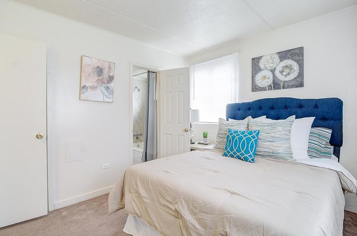 Bright and inviting bedroom featuring a plush blue headboard, stylish pillows, and elegant artwork.