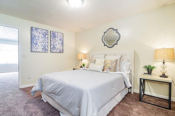 Inviting bedroom showcasing elegant decor, a plush bed with floral cushions, stylish wall art, and warm ambient lighting.