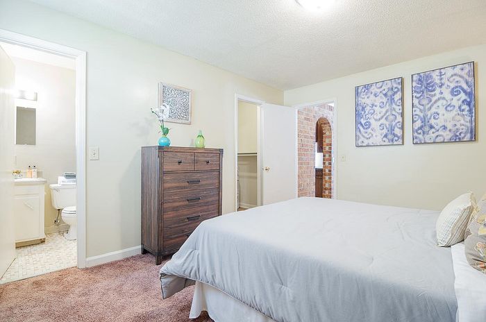 Inviting bedroom with plush carpeting, elegant decor, and an en-suite bathroom, perfect for relaxing in style.